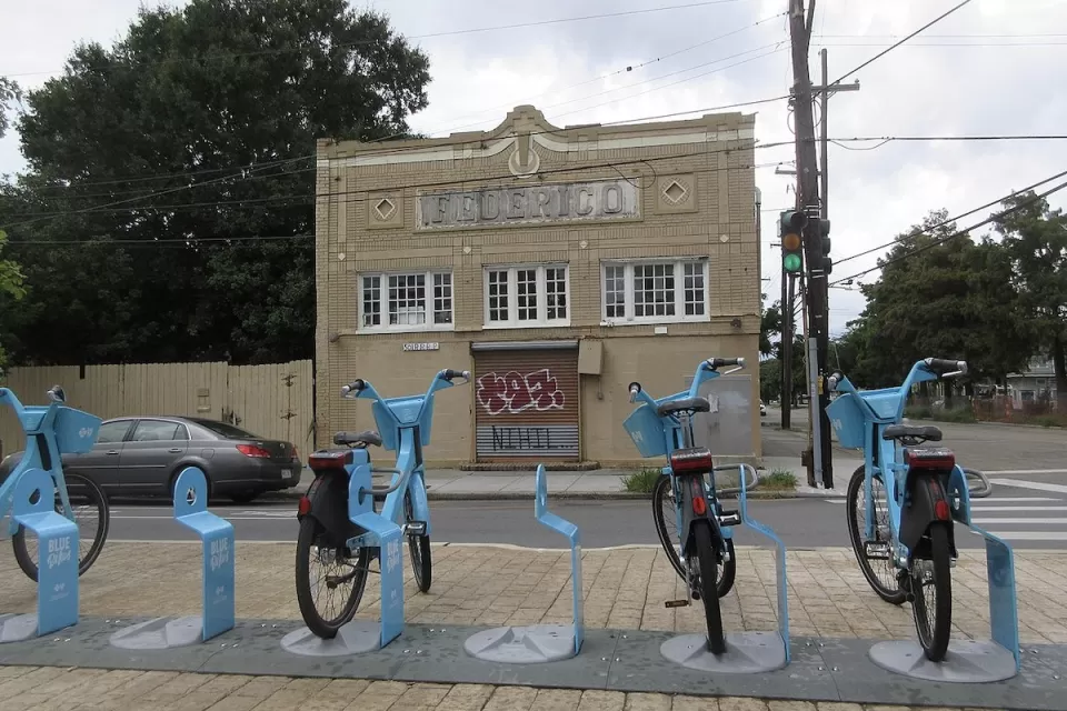 Row of blue Blue Bikes bike share bikes at docked station on sidewalk in New Orleans, Louisiana.